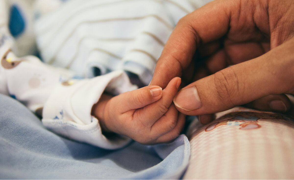 Foto van de hand van een pasgeboren baby en de vader